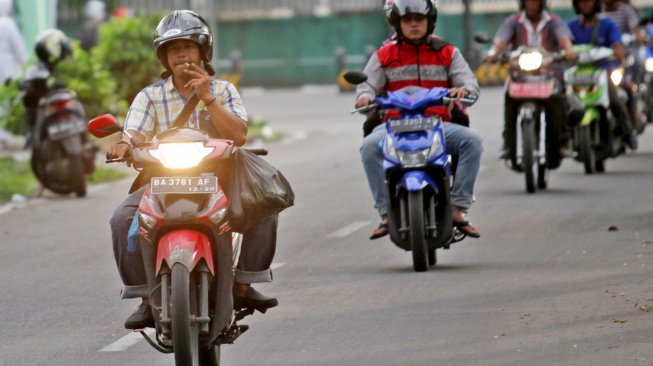 

Seorang pengendara merokok sambil mengendarai sepeda motor, di Padang, Sumatera Barat, Jumat (29/3). [ANTARA FOTO/Muhammad Arif Pribadi]