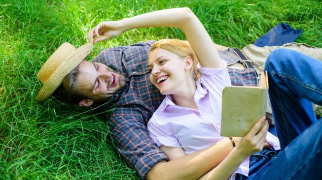 Pasangan kekasih sedang piknik sambil membaca buku. (Shutterstock)