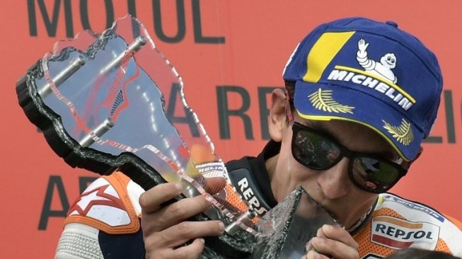 Rider Respol Honda Marc Marquez mencium trofi juaranya di podium setelah memenangi MotoGP Argentina di sirkuit Termas de Rio Hondo. Juan MABROMATA / AFP