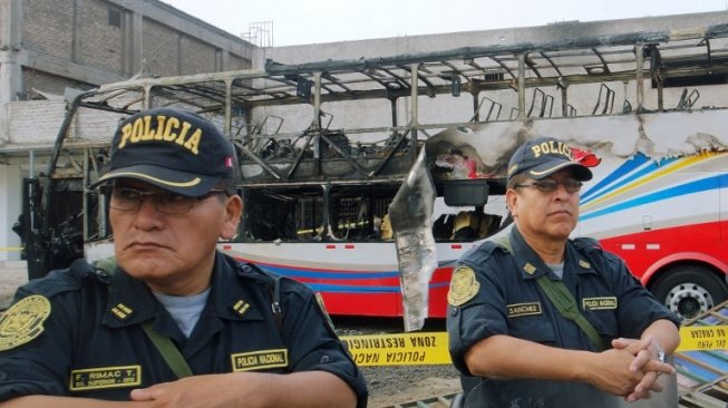 Petugas kepolisian Peru berjaga-jaga di lokasi terbakarnya bus yang menewaskan 20 orang. (AFP)