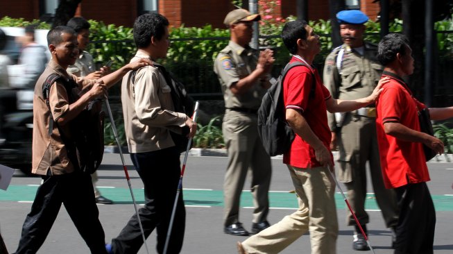 Sejumlah penyandang disabilitas membentuk regu iring - iringan menyusuri ubin pemandu yang dikhususkan bagi disabilitas netra di kawasan Blok M, Jakarta Selatan, Jakarta, Selasa (2/4). [Suara.com/Arief Hermawan P]