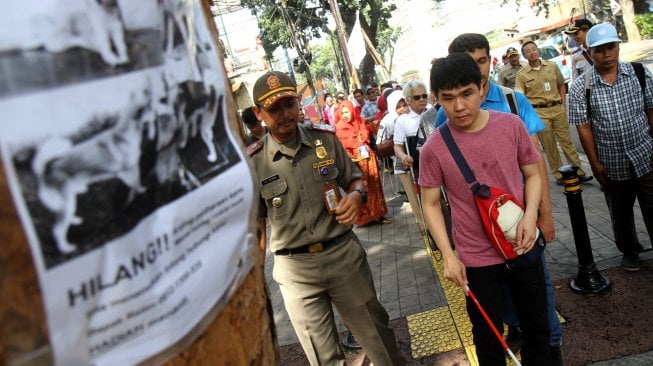 Sejumlah penyandang disabilitas membentuk regu iring - iringan menyusuri ubin pemandu yang dikhususkan bagi disabilitas netra di kawasan Blok M, Jakarta Selatan, Jakarta, Selasa (2/4). [Suara.com/Arief Hermawan P]