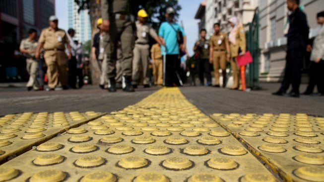 Sejumlah penyandang disabilitas membentuk regu iring - iringan menyusuri ubin pemandu yang dikhususkan bagi disabilitas netra di kawasan Blok M, Jakarta Selatan, Jakarta, Selasa (2/4). [Suara.com/Arief Hermawan P]