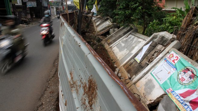 Kendaraan melintasi tembok yang roboh di Jalan Kebagusan Raya, Jakarta Selatan, Kamis (4/4). [Suara.com/Arief Hermawan P]