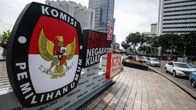 Petugas kebersihan melintas di dekat papan sosialisasi pemilu 2019 di kawasan Bundaran HI, Jakarta, Rabu (3/4).[ANTARA FOTO/Rivan Awal Lingga]
