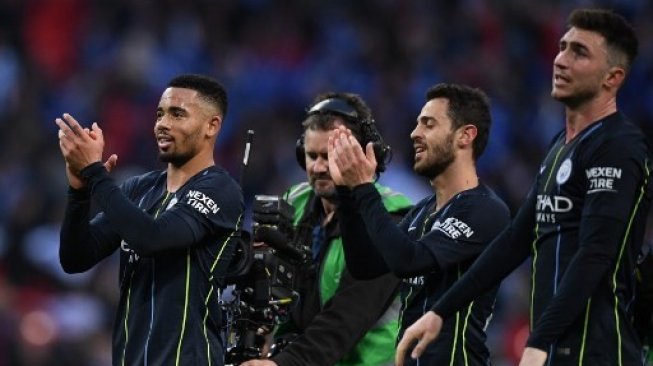 Pemain Manchester City Gabriel Jesus, Bernardo Silva dan Aymeric Laporte (kiri ke kanan) memberikan aplaus pada fans setelah mengalahkan Brighton and Hove Albion di semifinal Piala FA di Wembley Stadium. Daniel LEAL-OLIVAS / AFP