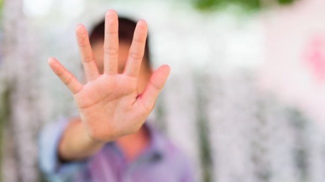 Seorang perempuan mengacungkan tangan tandan penolakan. Ilustrasi pelecehan seksual. [Shutterstock]