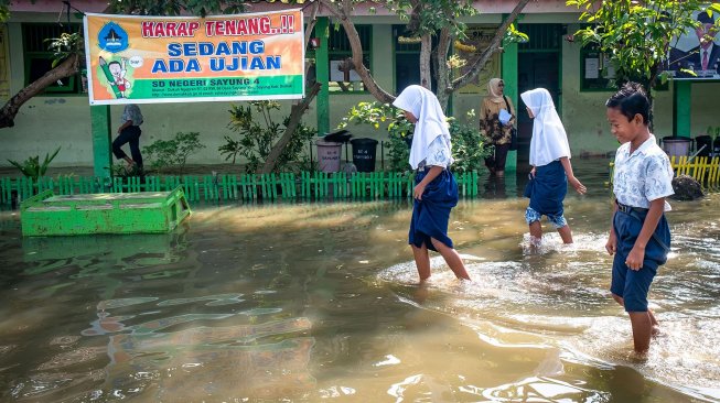 Sejumlah siswa SD kelas VI menembus halaman sekolah yang terendam banjir seusai mengikuti ujian sekolah di SD Negeri Sayung 4, Sayung, Demak , Jawa Tengah, Rabu (10/9). [ANTARA FOTO/Aji Styawan]