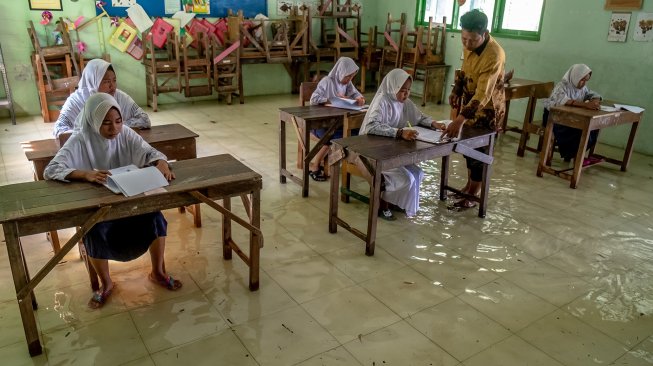 Sejumlah siswa SD kelas VI mengikuti ujian sekolah di ruang kelas yang terendam banjir di SD Negeri Sayung 4, Sayung, Demak , Jawa Tengah, Rabu (10/9). [ANTARA FOTO/Aji Styawan]