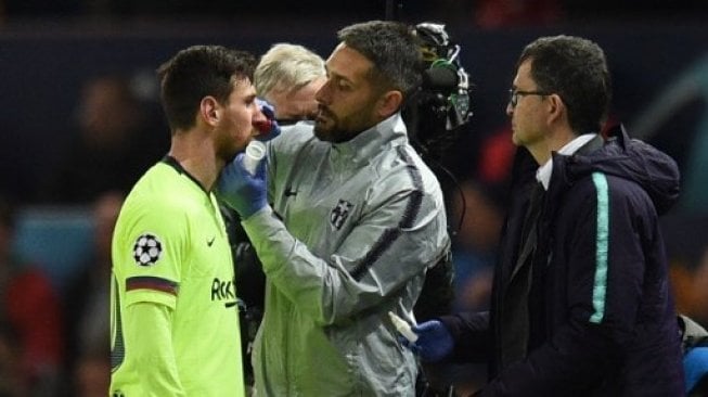 Kapten Barcelona Lionel Messi (kiri) mendapatkan perawatan tim medis setelah hidungnya berdarah terkena hantaman tangan pemain Manchester United saat laga Liga Champions di Old Trafford. Oli SCARFF / AFP