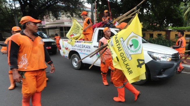 Sejumlah petugas PPSU menurunkan Alat Peraga Kampanye (APK) peserta Pemilu di Kawasan Imam Bonjol, Jakarta, Minggu (14/4). [Suara.com/Muhaimin A Untung]