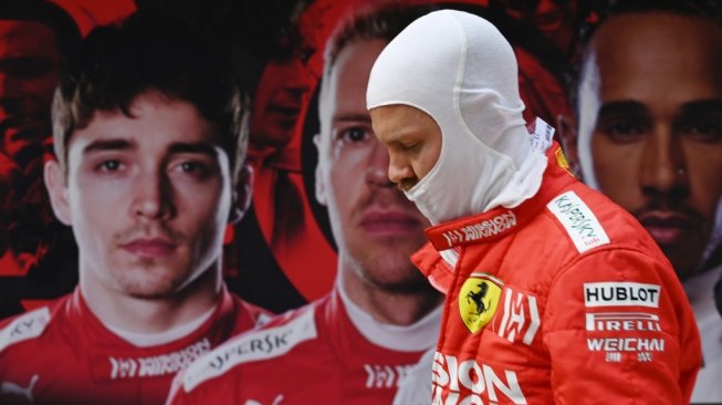 Driver Ferrari asal Jerman, Sebastian Vettel tengah melangkah kembali ke pit garage, melewati poster bergambar mitranya, Charles Leclerc (kiri), dirinya sendiri (tengah), dan driver Britania Raya, Lewis Hamilton (kanan), setelah sesi latihan kedua di F1 GP China 2019 (12/4/2019) [AFP/Greg Baker].