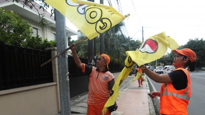 Sejumlah petugas PPSU menurunkan Alat Peraga Kampanye (APK) peserta Pemilu di Kawasan Imam Bonjol, Jakarta, Minggu (14/4). [Suara.com/Muhaimin A Untung]