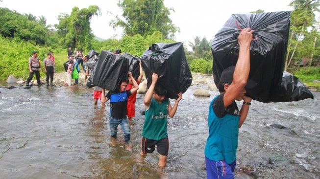 Sejumlah pekerja pengangkut barang (porter) menyeberangi sungai saat membawa logistik Pemilu serentak 2019 ke dua desa terpencil di kaki Pegunungan Meratus, Kabupaten Hulu Sungai Tengah, Kalimantan Selatan, Minggu (14/4). ANTARA FOTO/Bayu Pratama S