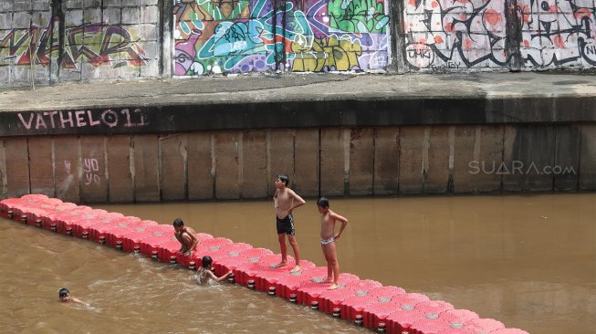 Sejumlah anak bermain di Sungai Ciliwung, Jakarta, Kamis (18/4). [Suara.com/Muhaimin A Untung]