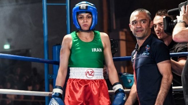 Petinju Putri Iran Sadaf Khadem (kiri) bersama sang pelatih Mahyar Monshipour (kedua dari kiri) dalam pertarungan melawan petinju Perancis Anne Chauvin dalam duel di Royan, Prancis, Sabtu (13/4/2019). [AFP/Mehdi Fedouach]