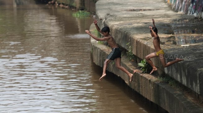 Sejumlah anak bermain di Sungai Ciliwung, Jakarta, Kamis (18/4). [Suara.com/Muhaimin A Untung]