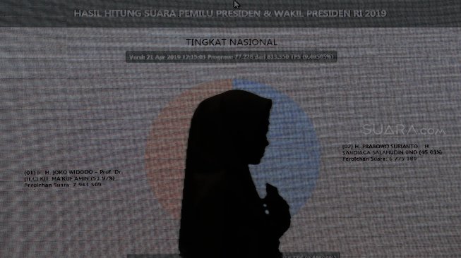 Siluet petugas didepan layar saat rekapitulasi penghitungan suara melalui aplikasi Situng di Kantor Komisi Pemilihan Umum (KPU), Jakarta, Minggu (21/4). [Suara.com/Muhaimin A Untung]