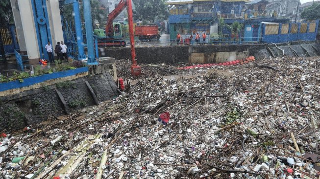 Alat berat melakukan pengangkatan sampah yang menumpuk di Pintu Air Manggarai, Jakarta, Rabu (24/4). [Suara.com/Muhaimin A Untung]
