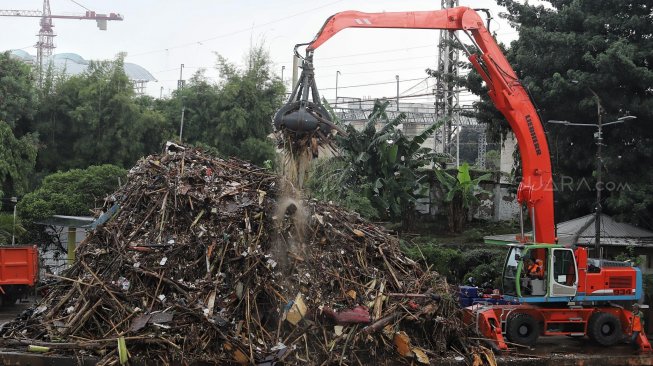 Alat berat melakukan pengangkatan sampah yang menumpuk di Pintu Air Manggarai, Jakarta, Rabu (24/4). [Suara.com/Muhaimin A Untung]
