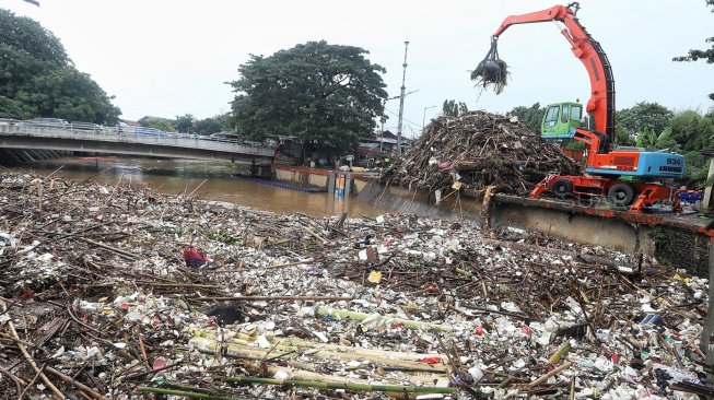 Alat berat melakukan pengangkatan sampah yang menumpuk di Pintu Air Manggarai, Jakarta, Rabu (24/4). [Suara.com/Muhaimin A Untung]
