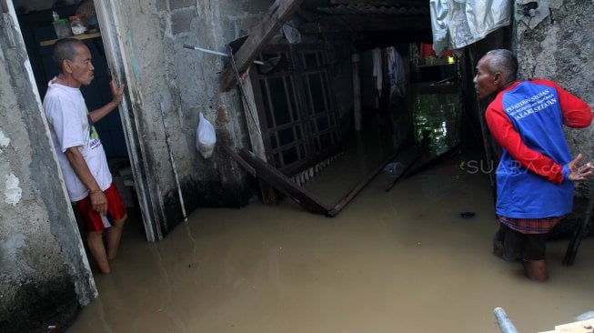 Warga memeriksa barang-barang didalam rumah yang tergenang banjir di kawasan Kampung Jawa, Pejaten Timur, Jakarta Selatan, Jumat (26/4). [Suara.com/Arief Hermawan P]