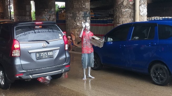 Roni (35) perantau asal Cirebon, Jawa Barat memilih bekerja menjadi pengamen manusia silver di Jalan KH. Noer Ali, Bekasi Barat.