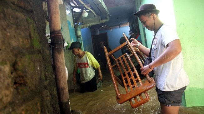 Warga memeriksa barang-barang didalam rumah yang tergenang banjir di kawasan Kampung Jawa, Pejaten Timur, Jakarta Selatan, Jumat (26/4). [Suara.com/Arief Hermawan P]