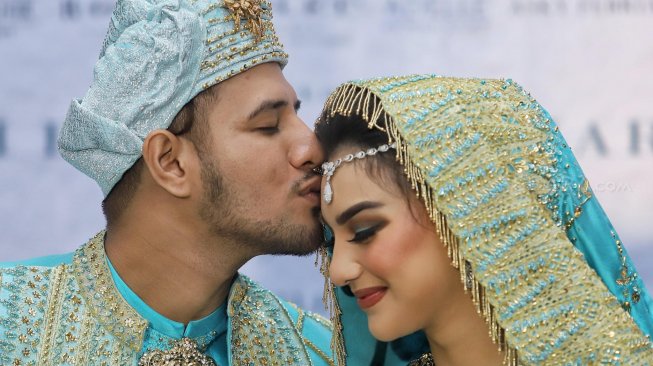 Ammar Zoni saat mencium kening Irish Bella usai akad nikah di Bandung, Jawa Barat, Minggu (28/4). [Suara.com/Muhaimin A Untung]