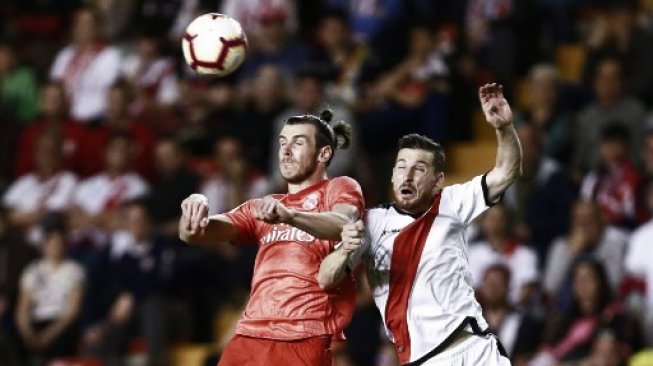 Penyerang Real Madrid, Gareth Bale (kiri), berduel udara dengan bek Rayo Vallecano, Tito, kala kedua tim bertemu pada lanjutan La Liga Spanyol di Estadio de Vallecas, Senin (29/4/2019) dini hari WIB. [AFP/Benjamin Cremel]