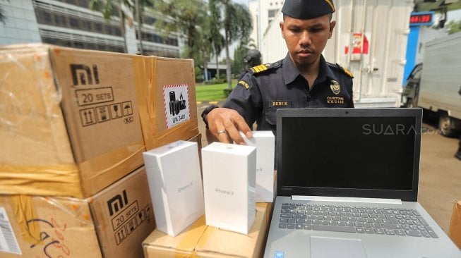 Polisi dan Petugas Direktorat Jenderal Bea Cukai memperlihatkan barang bukti saat rilis Hasil Penindakan Telepon Genggam, Tablet, Laptop dan Alat Elektronik di Lapangan Hitam Parkiran Kantor Pusat Direktorat Jenderal Bea dan Cukai, Jakarta, Selasa (30/4). [Suara.com/Muhaimin A Untung]