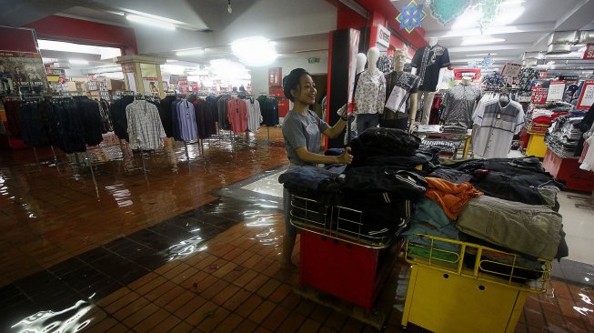 Seorang karyawan menata pakaian di Hi-Tech Mall yang terendam banjir di Surabaya, Jawa Timur, Senin (29/4). [ANTARA FOTO/Moch Asim]