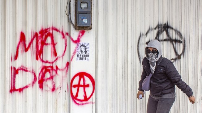 Seorang buruh dari Aliansi Buruh Karawang melakukan aksi vandalisme saat mengikuti aksi Hari Buruh Internasional (May Day) di klawasan By Pass, Karawang, Jawa Barat, Rabu (1/5/2019). [Antara/M Ibnu Chazar]