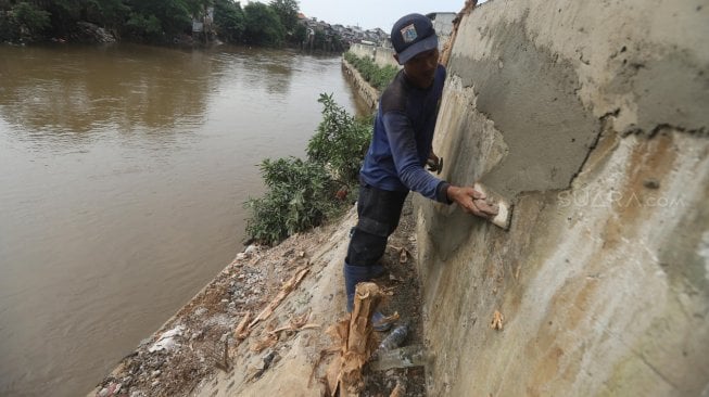 Sejumlah pasukan Sumber Daya Air DKI Jakarta memperbaiki tanggul sungai Ciliwung, Jakarta, Jumat (3/5).[Suara.com/Muhaimin A Untung]