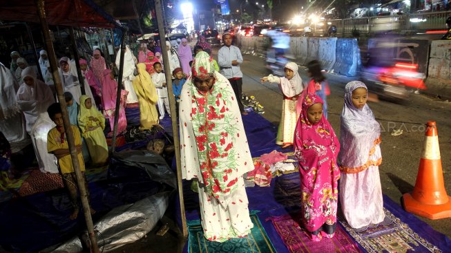 Umat muslim menunaikan ibadah shalat Tarawih pertama di JPO dan halaman Musholla Miftahul Janah, Pasar Gembrong, Jakarta, Minggu (5/5). [Suara.com/Arief Hermawan P]