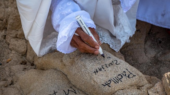 Peziarah menuliskan nama kerabatnya di kawasan bukit Jabal Rahmah, Padang Arafah, Makkah Al Mukarramah, Arab Saudi, Sabtu (4/5). ANTARA FOTO/Aji Styawan