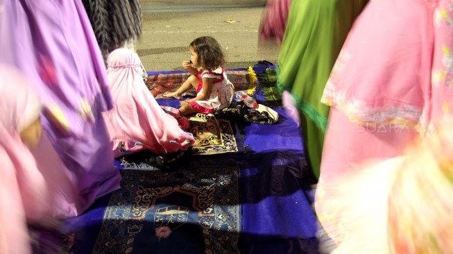 Umat muslim menunaikan ibadah shalat Tarawih pertama di JPO dan halaman Musholla Miftahul Janah, Pasar Gembrong, Jakarta, Minggu (5/5). [Suara.com/Arief Hermawan P]