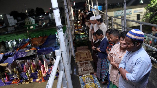 Umat muslim menunaikan ibadah shalat Tarawih pertama di JPO dan halaman Musholla Miftahul Janah, Pasar Gembrong, Jakarta, Minggu (5/5). [Suara.com/Arief Hermawan P]