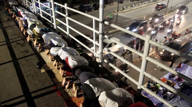 Umat muslim menunaikan ibadah shalat Tarawih pertama di JPO dan halaman Musholla Miftahul Janah, Pasar Gembrong, Jakarta, Minggu (5/5). [Suara.com/Arief Hermawan P]