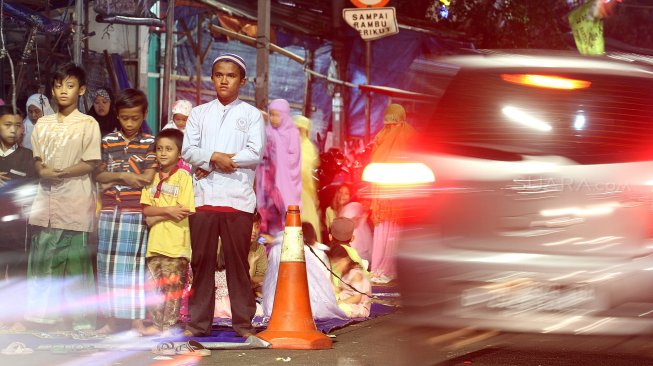 Umat muslim menunaikan ibadah shalat Tarawih pertama di JPO dan halaman Musholla Miftahul Janah, Pasar Gembrong, Jakarta, Minggu (5/5). [Suara.com/Arief Hermawan P]