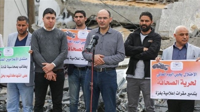 Perwakilan Anadolu dari Gaza Yasser al-Benna (tengah) berbicara saat demonstrasi ketika para wartawan berkumpul di depan puing-puing kantor Berita Anadolu yang hancur setelah diserang oleh pesawat tempur Israel. (Mustafa Hassona - Anadolu Agency)