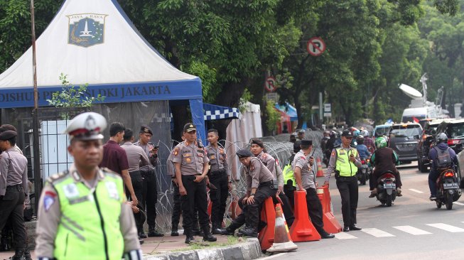 Sejumlah personel Kepolisian berjaga di sekitar kantor KPU yang dipasangi kawat berduri di Jalan Imam Bonjol, Jakarta, Kamis (9/5). [Suara.com/Arief Hermawan P]
