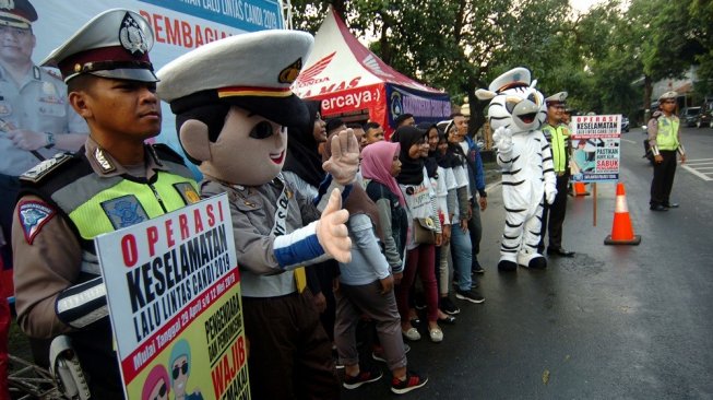 Anggota kepolisian memegang poster saat sosialisasi tertib berlalu lintas dan pembagian takjil di depan Polres Tegal, Jawa Tengah, Kamis (9/5/2019). Pembagian takjil dan helm kepada pengguna jalan jelang waktu berbuka puasa itu sebagai bentuk rasa kepedulian dan sosialisasi tertib lalu lintas serta berkendara yang aman pada bulan Ramadan [ANTARA FOTO/Oky Lukmansyah].