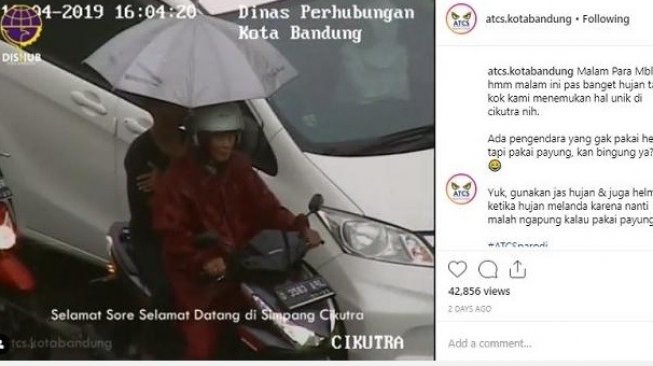 Hujan-hujan berpayung naik motor. Bisa-bisa si payung membuat orang keculek [Instagram: @atcs.kotabandung]