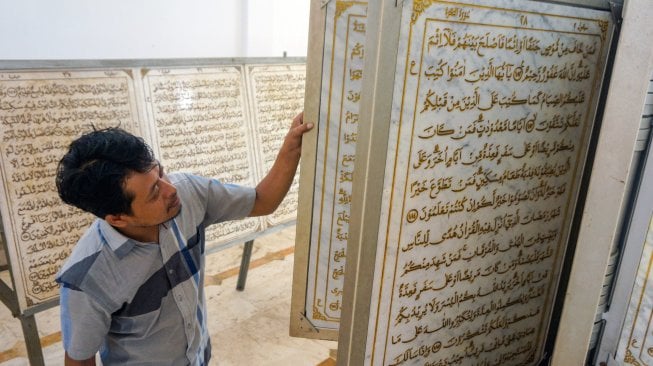 Warga mengamati ukiran huruf Al Quran di batu marmer di Masjid Al Muhtarom, Kabupaten Pekalongan, Jawa Tengah, Minggu (12/5). [ANTARA FOTO/Harviyan Perdana Putra]