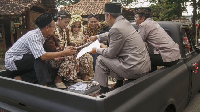 Pasangan pengantin naik mobil antik saat Nikah Bareng di Kampung Mataram, Bantul, DI Yogyakarta, MInggu (12/5). [ANTARA FOTO/Hendra Nurdiyansyah]