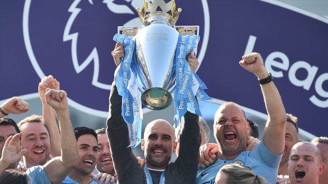 Manajer Manchester City Pep Guardiola mengangkat trofi juara Premier League setelah skuatnya mengalahkan Brighton and Hove Albion di pekan terakhir Liga Inggris. Glyn KIRK / AFP
