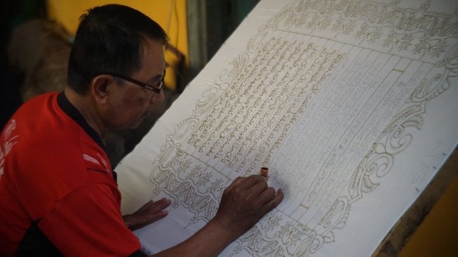 Seorang perajin tengah membuat Alquran batik. (Suara.com/Ari Purnomo)