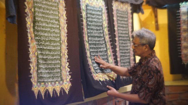 Seorang perajin tengah membuat Alquran batik. (Suara.com/Ari Purnomo)