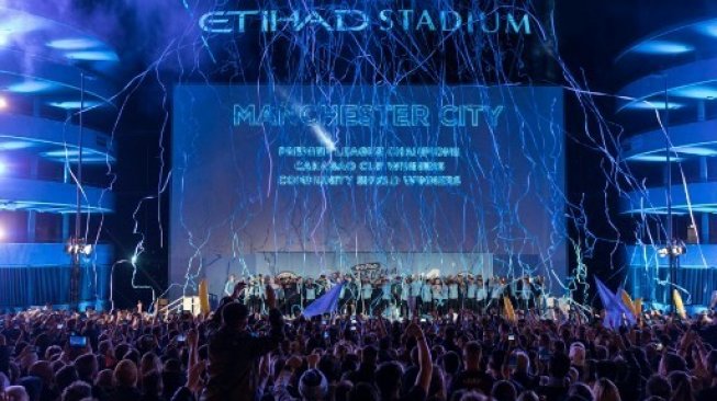 Para pemain Manchester City, dan staff pelatih merayakan keberhasilannya mengangkat trofi Premier League dengan para suporternnya di luar Etihad Stadium. OLI SCARFF / AFP